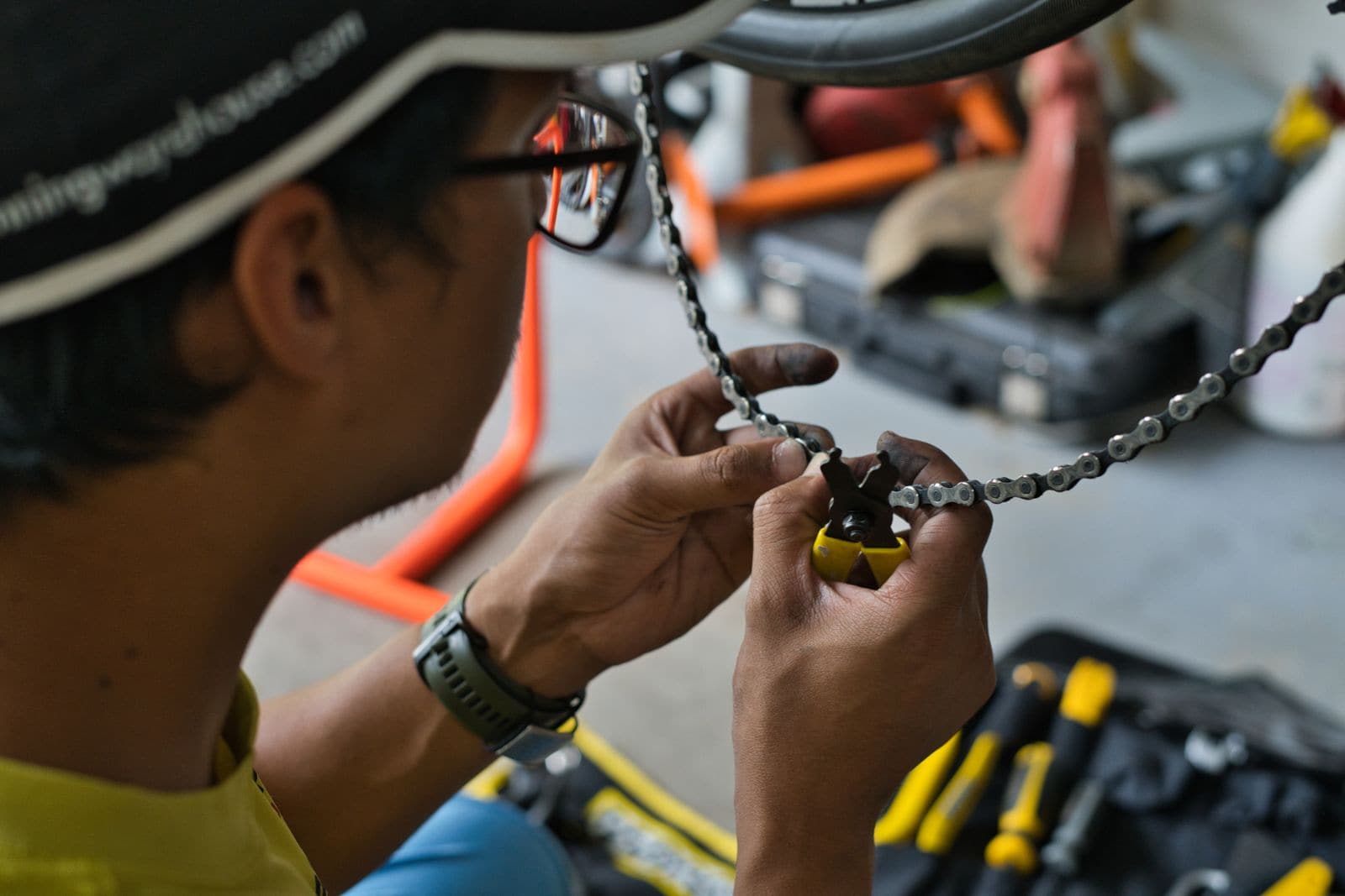 Mechanic using a chain tool on a bicycle chain beside a set of tools