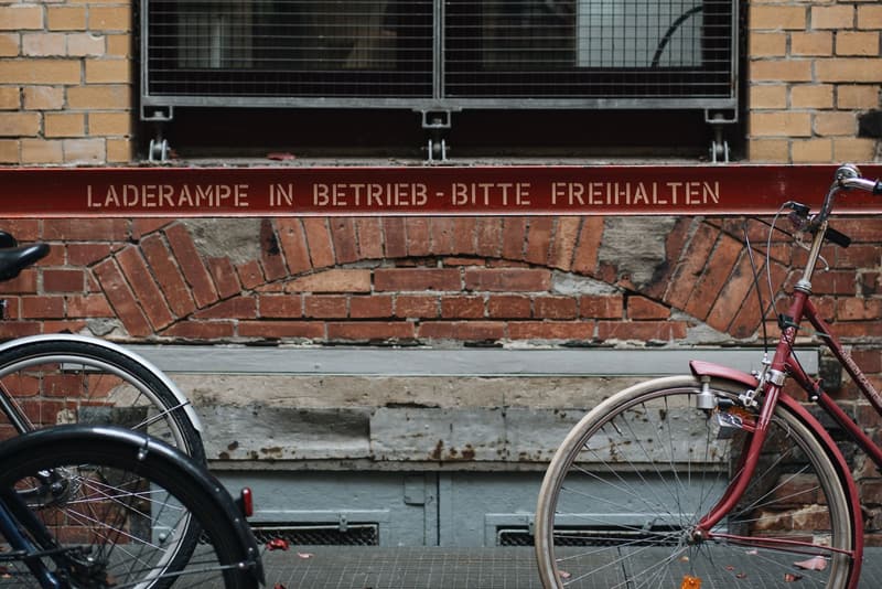 Two bicycles parked at a brick building with a German loading-bay sign