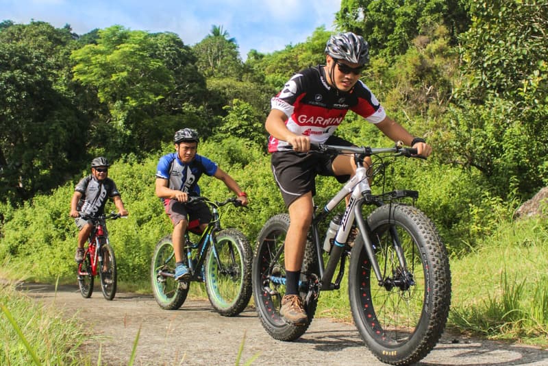Group of cyclists wearing helmets climbing a gravel road