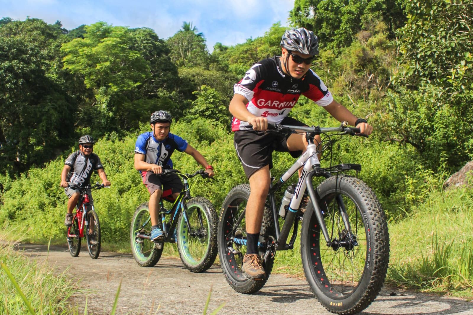 Group of cyclists wearing helmets climbing a gravel road