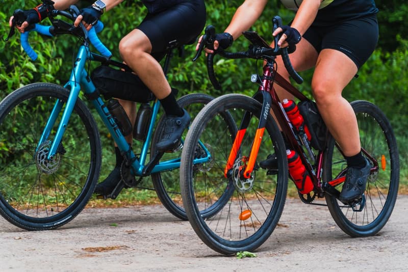Two gravel bikes with wide knobbly tyres rolling along a gravel track