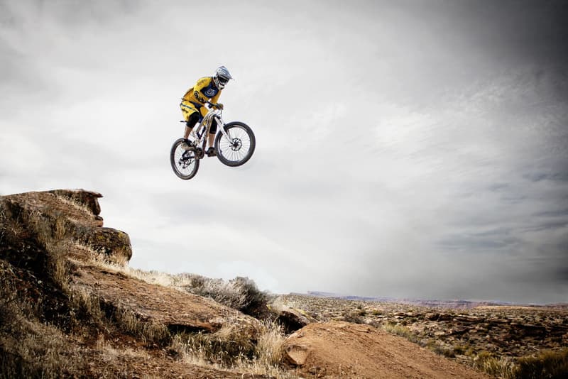 Mountain biker launching off a rocky drop on dry open terrain