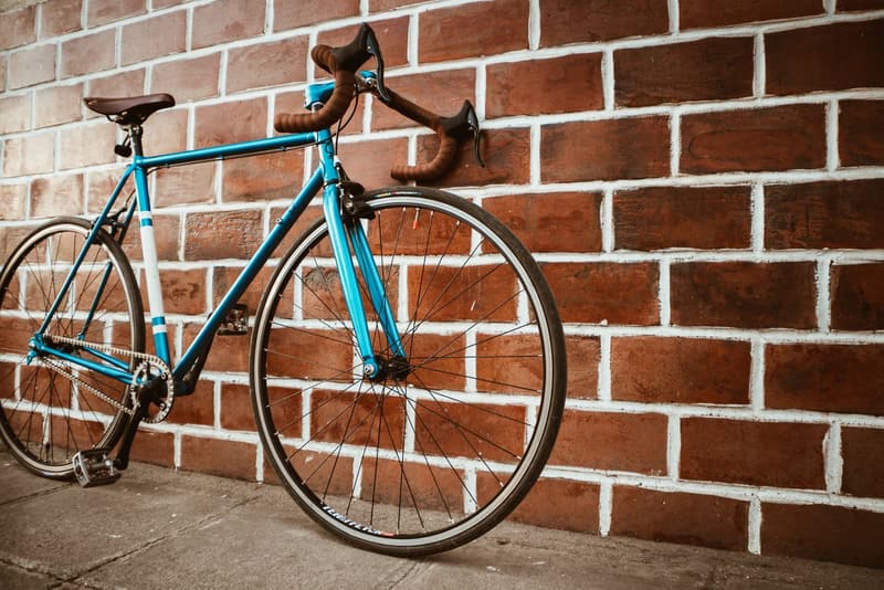 Steel road bicycle with drop handlebars leaning against a brick wall